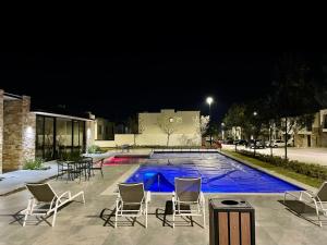 a group of chairs and a swimming pool at night at Private Room Bunk Bed Queretaro Entrance in Miranda