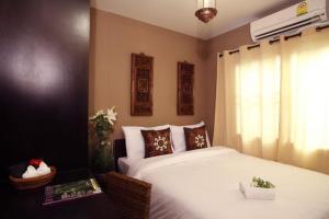 - une chambre avec un grand lit blanc et une fenêtre dans l'établissement Lilu Chiang Mai, à Chiang Mai