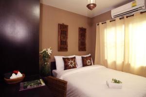 a bedroom with a large white bed with a window at Lilu Chiang Mai in Chiang Mai