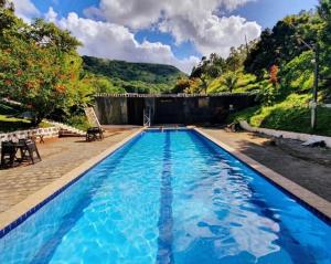 a swimming pool with blue water and mountains in the background at Flat Térreo condomínio Pedra do Rodeaoduro in Bonito