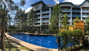 a hotel with a swimming pool in front of a building at Studio Unit at Pine Suites Tagaytay in Tagaytay