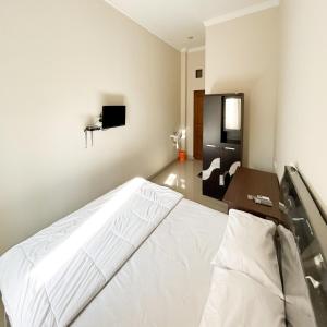 a bedroom with a white bed and a tv at Queen Belt Mitra Reddoorz in Balong
