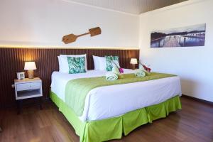 a bedroom with a large bed with green and white sheets at Hare Nua Hotel Boutique in Hanga Roa