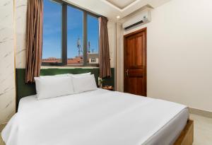 a bedroom with a white bed and a window at Trang Ngan Hotel by THG in Danang