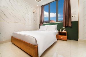 a bedroom with a bed and a window at Trang Ngan Hotel by THG in Danang