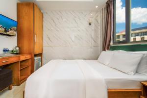a bedroom with a white bed and a window at Trang Ngan Hotel by THG in Danang