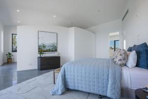 a white bedroom with a bed and a bathroom at Blue Seas in Lennox Head
