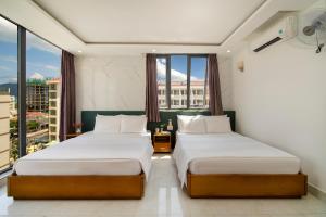 two beds in a room with a large window at Trang Ngan Hotel by THG in Danang