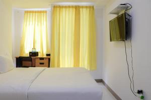 a bedroom with a white bed and a television at Compact and Tidy Studio at Tokyo Riverside PIK 2 Apartment By Travelio in Rawalembang