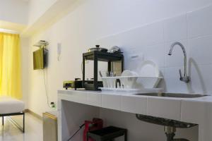 a kitchen with a sink with dishes on it at Compact and Tidy Studio at Tokyo Riverside PIK 2 Apartment By Travelio in Rawalembang +12 photos