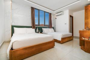 a bedroom with two beds and a window at Trang Ngan Hotel by THG in Danang