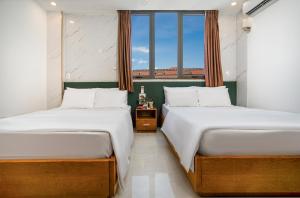 two beds in a room with a window at Trang Ngan Hotel by THG in Danang