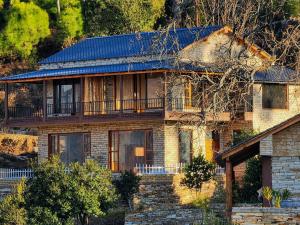 a brick house with a balcony on top of it at The Himalayan Stone Hamlet in Mukteshwar