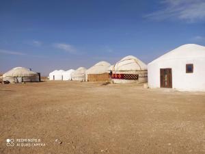 a row of domed buildings in a desert with a sky at Ayazkala yurt camp in Bŭston