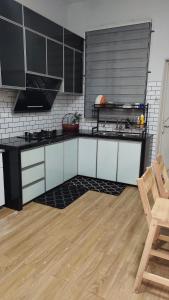 a kitchen with black and white cabinets and a wooden floor at Homestay Ar-Rayyan in Pokok Sena