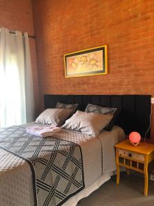 a bedroom with a bed with a picture on the wall at Pousada Santosha in Camanducaia