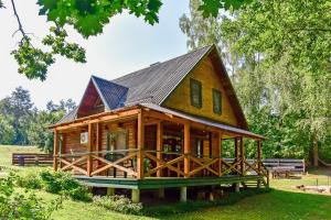 a large wooden cabin with a gambrel roof at Ažuluokesos sodyba in Molėtai