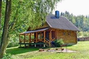 a log cabin in a field with a tree at Ažuluokesos sodyba in Molėtai