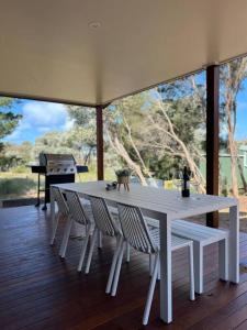 Una mesa blanca y sillas en una terraza con un piano. en Golden Beach Beauty!, en Paradise Beach