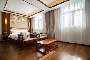 een slaapkamer met een bed, een bank en een tafel bij Pierr Palace Hotel (Beijing Nanluo Guxiang) in Beijing