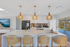 una cocina con una gran isla blanca con sillas en Lakeside Retreat, en Long Jetty