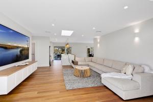 sala de estar con sofá y TV de pantalla grande en Lakeside Retreat, en Long Jetty