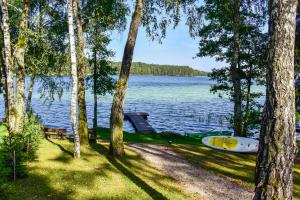 a boat on the shore of a lake with trees at Ažuluokesos sodyba in Molėtai