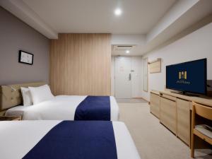 东京hotel MONday Haneda Airport的一间配有两张床和一台平板电视的酒店房间