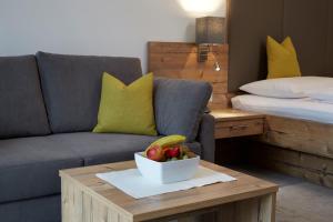 a living room with a couch and a bowl of fruit on a table at Hotel Zum Mohren in Reutte