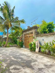 a house with a wooden gate and a palm tree at Joglo Breeze Guesthouse and Villa in Tabanan