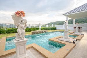 a statue of a child on a column next to a pool at Luxurious 4-Bedroom Pool Villa Best Mountain Views in Hua Hin