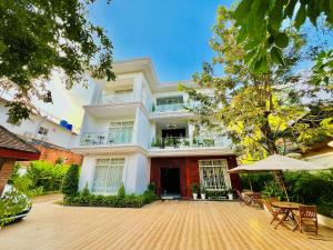 a large white building with chairs and an umbrella at NyNa Villa Guesthouse in Kampot