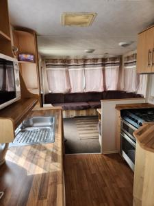 an rv kitchen with a sink and a stove at Ingoldmells, The Grange Holiday Park 3-Bedroom Caravan in Skegness