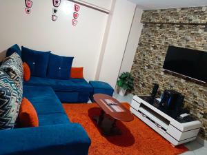 a living room with a blue couch and a tv at Jayson Furnished Apartment, Nairobi in Nairobi