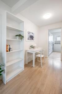 a white dining room with a white table and shelves at Book an apartment just for you in central Tromsø in Tromsø