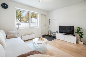 a living room with a white couch and a tv at Book an apartment just for you in central Tromsø in Tromsø