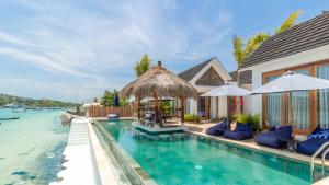 a swimming pool with chairs and umbrellas next to a house at Segara Seaside Resort in Nusa Lembongan