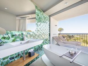 a bathroom with a tub and a sink and a balcony at Immerso Hotel, a Member of Design Hotels in Ericeira