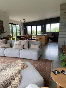 a living room with two couches and a kitchen at The Coastal Retreat in Raglan