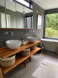a bathroom with two sinks and a tub and a mirror at The Coastal Retreat in Raglan