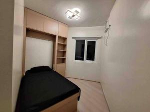 a small bedroom with a bed and a window at 2-Bedroom Condo with Swimming Pool in Manila +10 photos