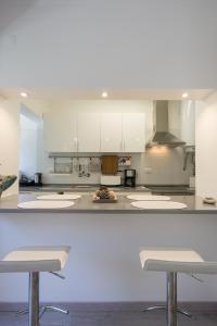 リスボンにあるLovely & Modern in the Centerの白いキャビネットとバースツール3つ付きのキッチン