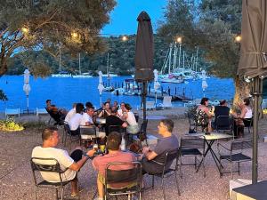 a group of people sitting at tables near a body of water at Amphitheatro Boutique Hotel in Meganisi