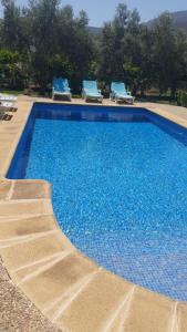 a large blue swimming pool with some blue chairs at Casa María in Órgiva