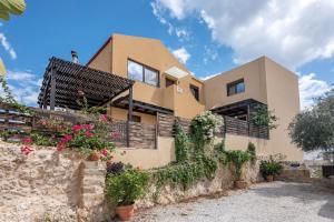 a house with a stone wall and flowers at VenMar luxury house in Plataniás