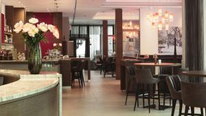 Un restaurante con mesas y sillas y un jarrón de flores. en City Hotel Merano, en Merano