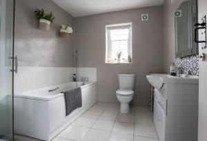a bathroom with a tub and a toilet and a sink at Ballymultimber Cottages - traditional cottages on the Causeway Coast in Limavady +48 photos