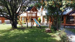 un parque infantil con un tobogán en un patio en Cabañas Maite en Villa La Angostura