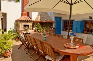 a wooden table with chairs and an umbrella on a patio at Ioannidis - Sigri Studios in Sígrion