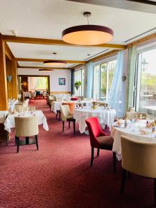 a restaurant with white tables and chairs and windows at Logis Hôtel-Restaurant Aux Trois Roses in La Petite-Pierre